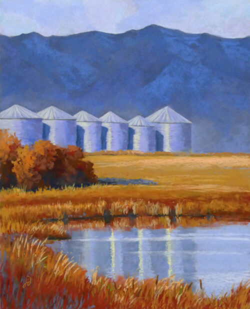 Photo of a pastel painting of six silos with mountains behind and a pond in front.